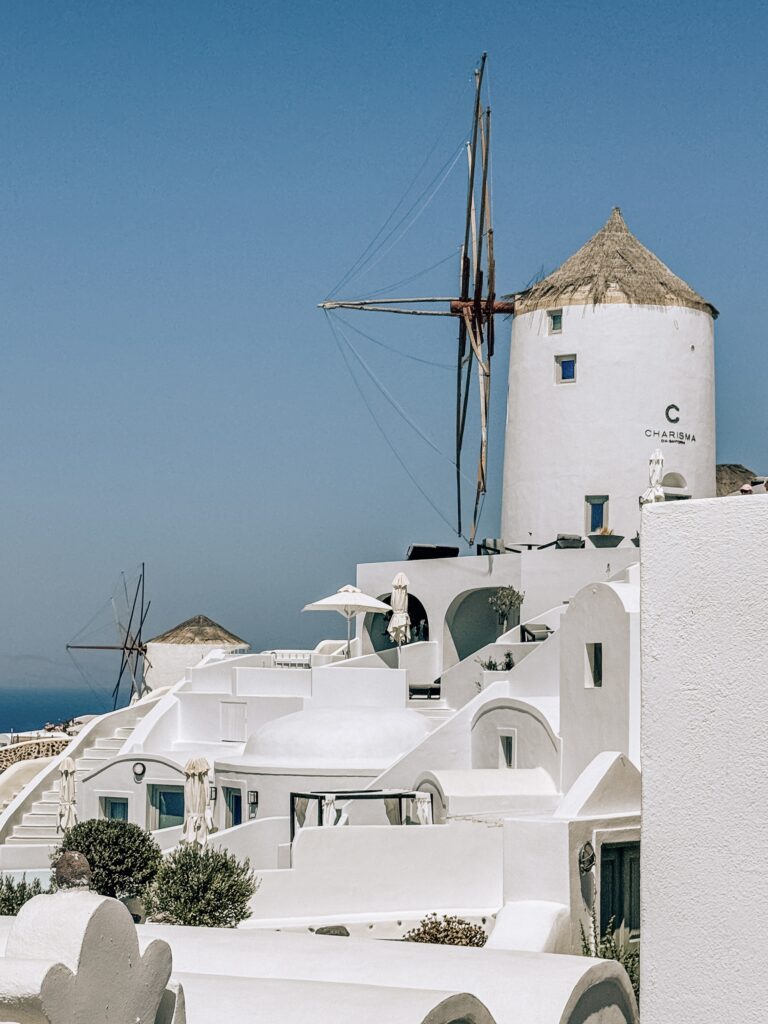 Traditional windmills in Oia, Santorini, standing blue skies and whitewashed buildings