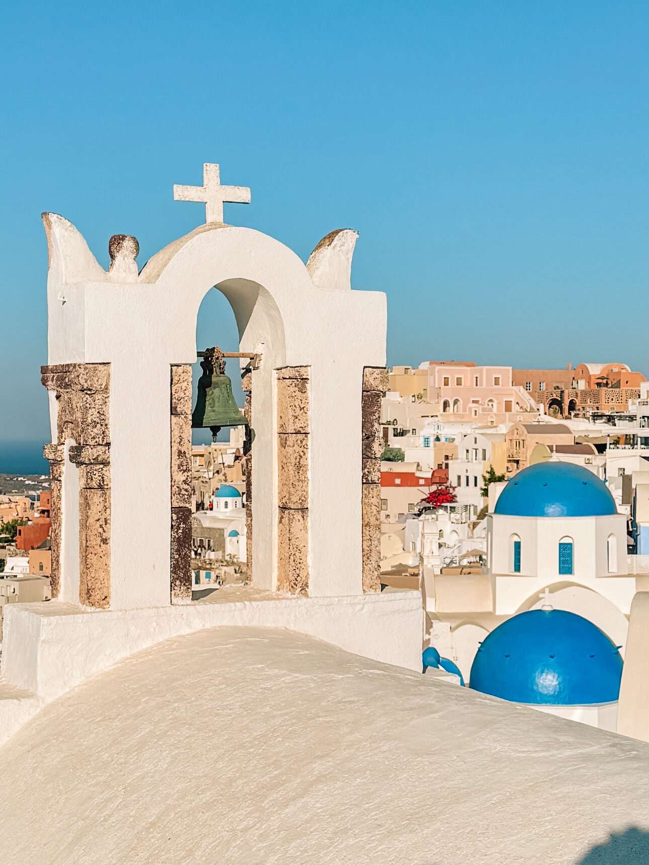 Iconic blue-domed churches and a church bell in Oia, Santorini
