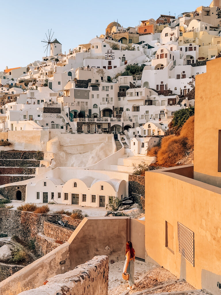 300 steps leading down to Amoudi Bay with views of whitewashed buildings and Oia Windmill, taken during sunset. 
