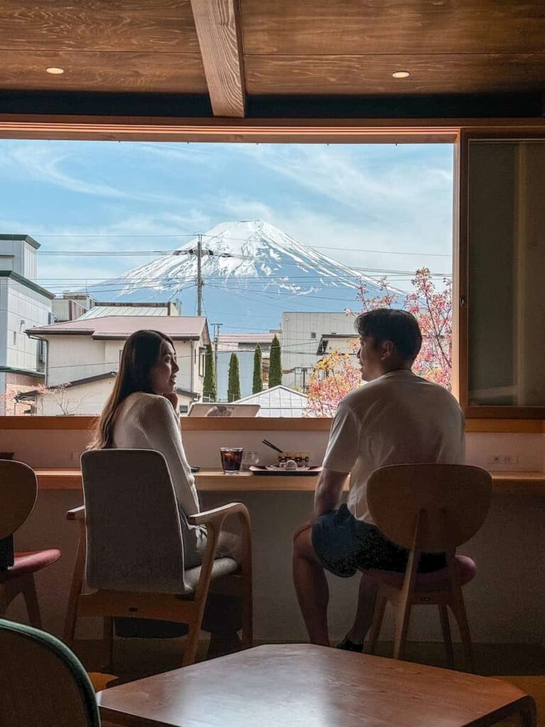 Couple sitting inside a café with a large window framing a perfect view of Mount Fuji outside.