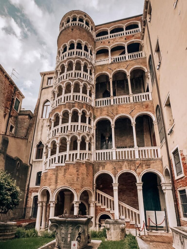 The ornate spiral staircase and arched loggias of Palazzo Contarini del Bovolo rising above a quiet courtyard in Venice.
