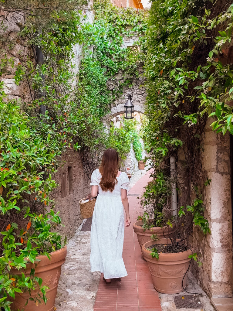 A woman walking down narrow alleyways of Medieval Eze Village France
