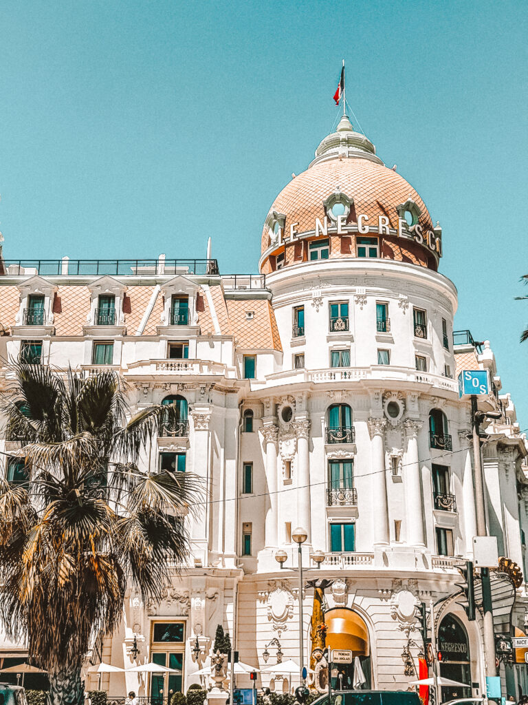 Facade of Hotel Le Negresco on Promenade des Anglais with palm trees
