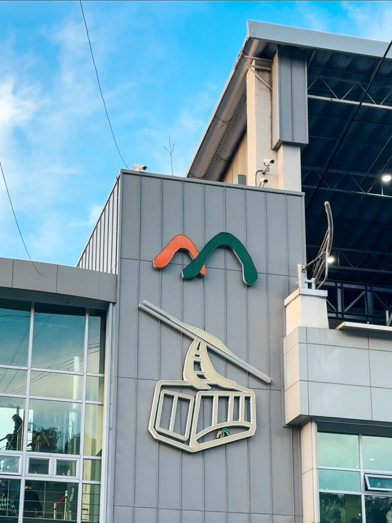 Exterior of the Namsan Cable Car station, featuring a modern building with a large cable car logo and mountain-shaped iconography.