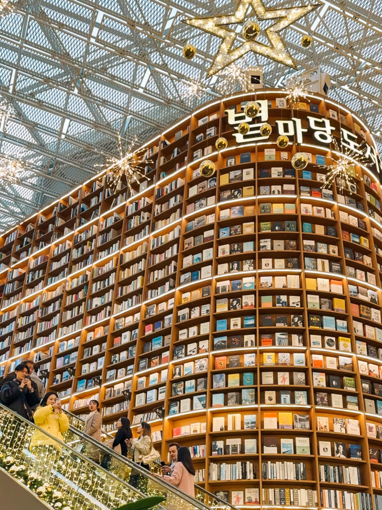 Escalator scene at Starfield Library with a towering curved bookshelf and Christmas decorations.