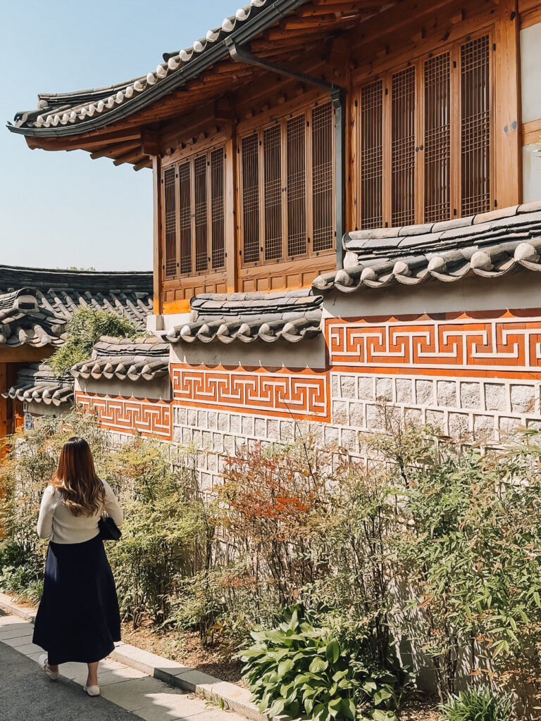Close-up view of a hanok wall with vibrant red geometric patterns and wooden window shutters in Bukchon Hanok Village.