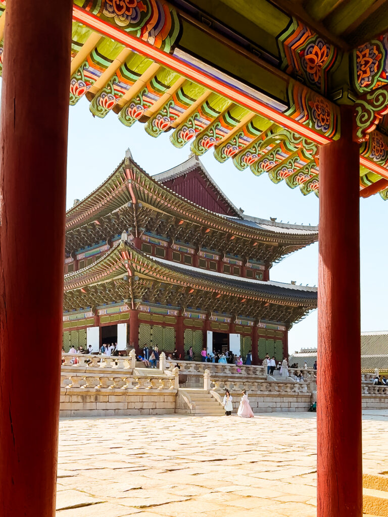 A striking view of Gyeongbokgung Palace’s main throne hall framed symmetrically by red wooden columns and vibrantly painted eaves.