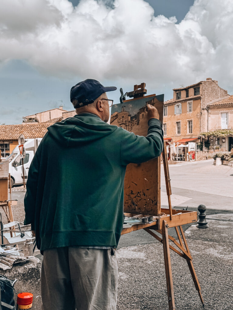 Local artist capturing the village on canvas in the heart of Gordes, with historic houses in the background.