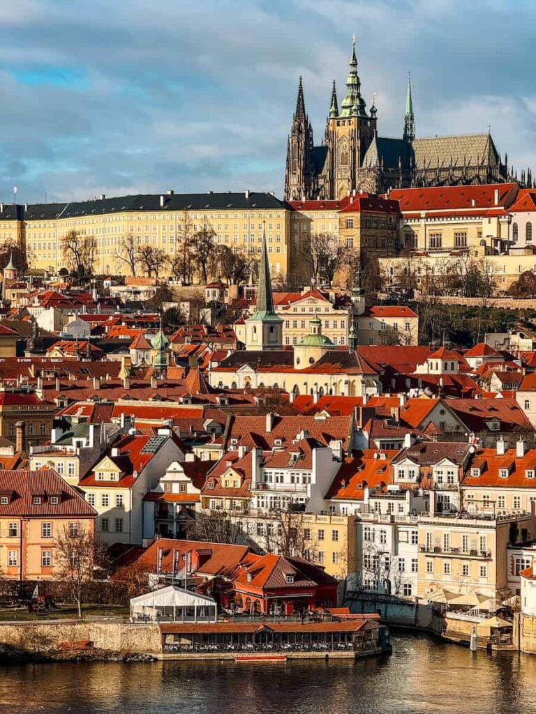 Scenic view of Prague Castle and St. Vitus Cathedral overlooking the red-roofed houses of Lesser Town (Malá Strana) across the Vltava River.