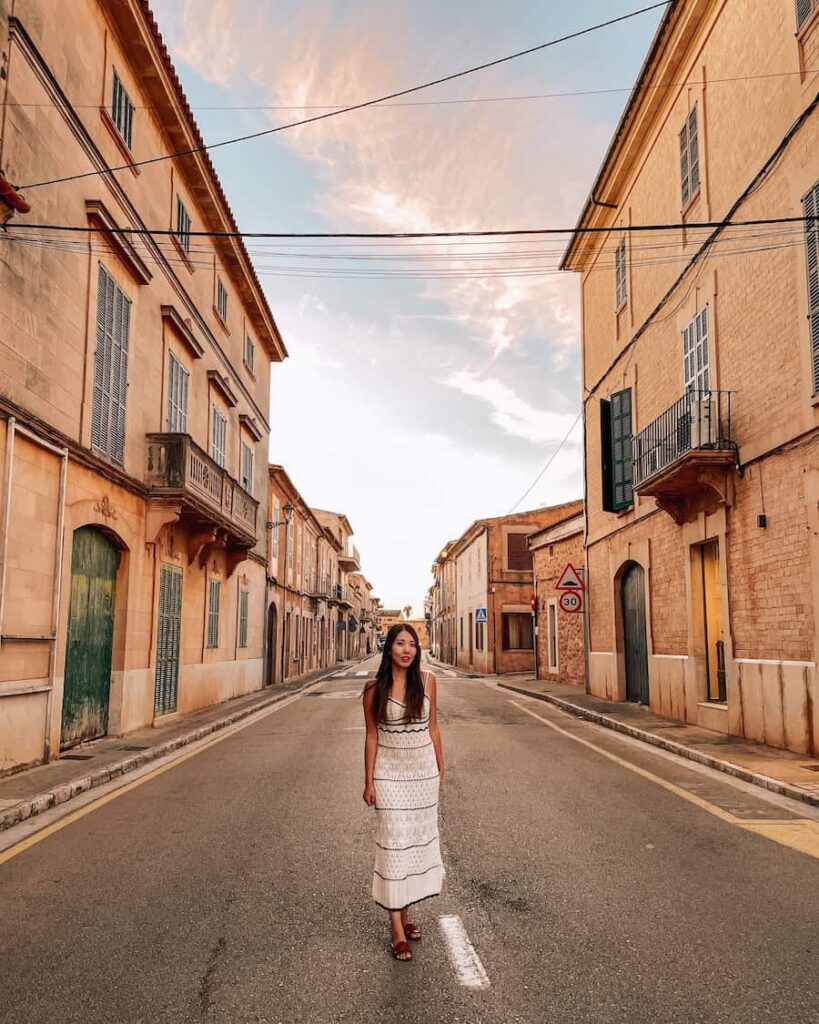 A woman wearing a striped crochet dress standing in the streets of Santanyi during her Mallorca itinerary