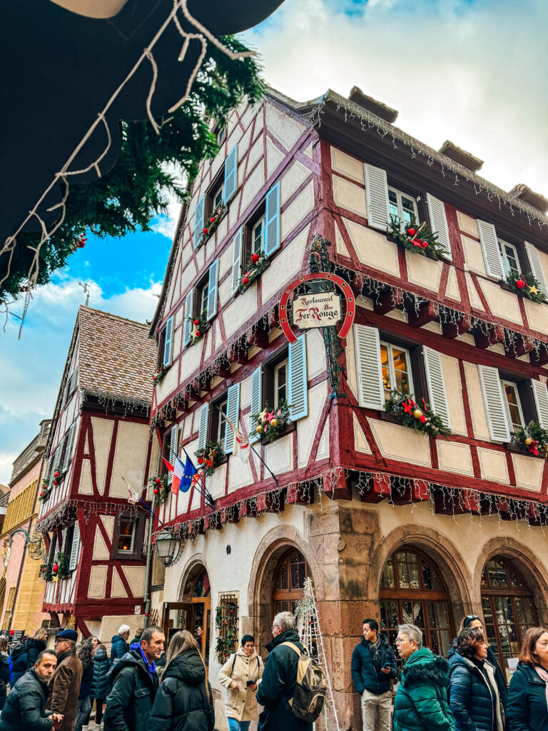 Traditional Alsatian half timbered house in Colmar decorated with ornaments and garlands during the Christmas market season.