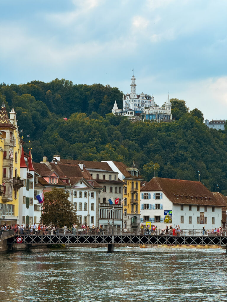 Colorful riverside buildings with the fairytale-like Château Gütsch perched on the hill.