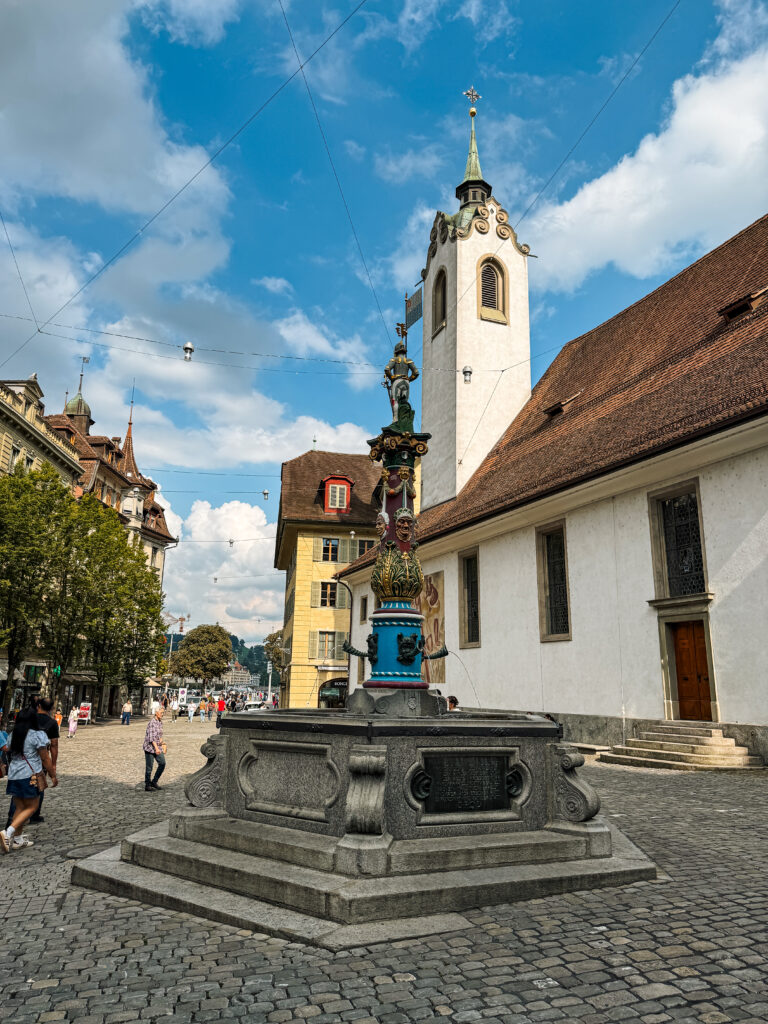 A Renaissance-style fountain in a cobblestone square surrounded by historic buildings.