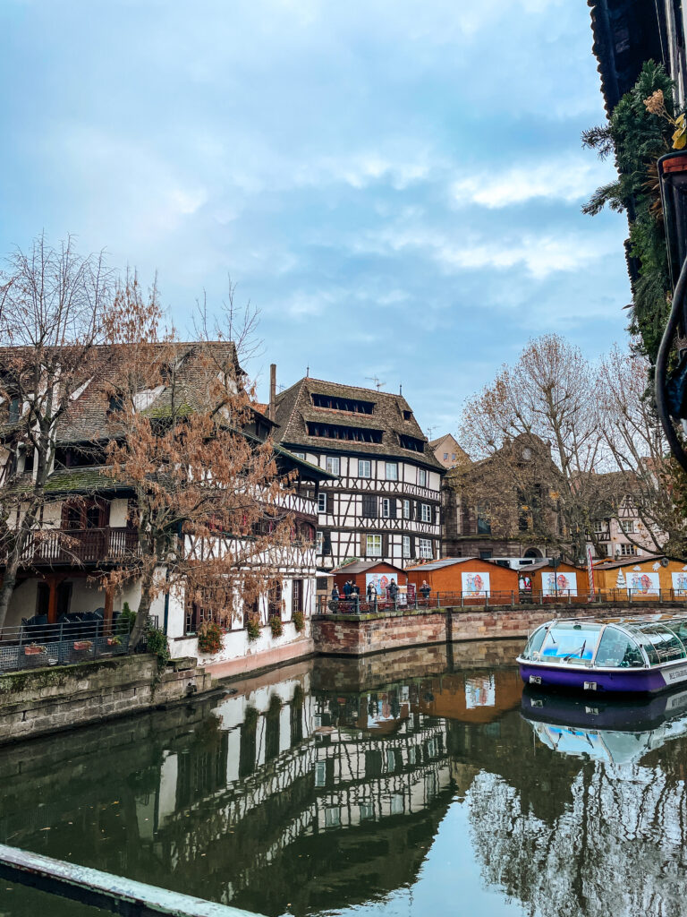 Traditional half timbered houses lining the canal in Petite France Strasbourg with a sightseeing boat.