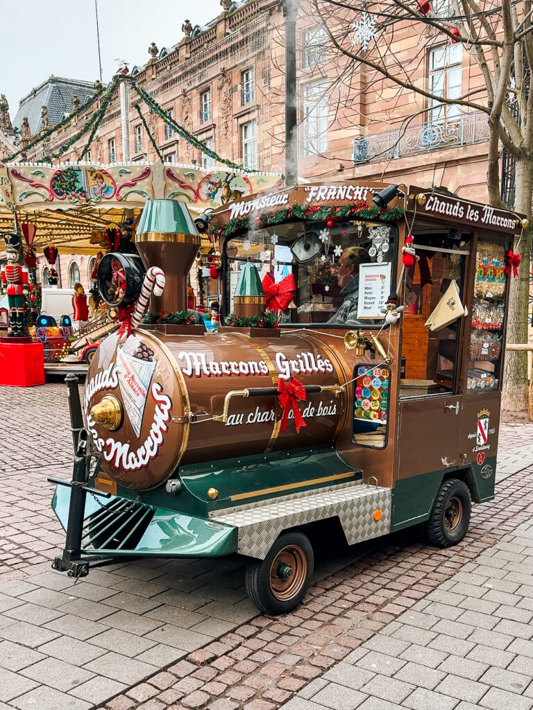 Festive mobile stall shaped like a train selling roasted chestnuts at Strasbourg Christmas market.