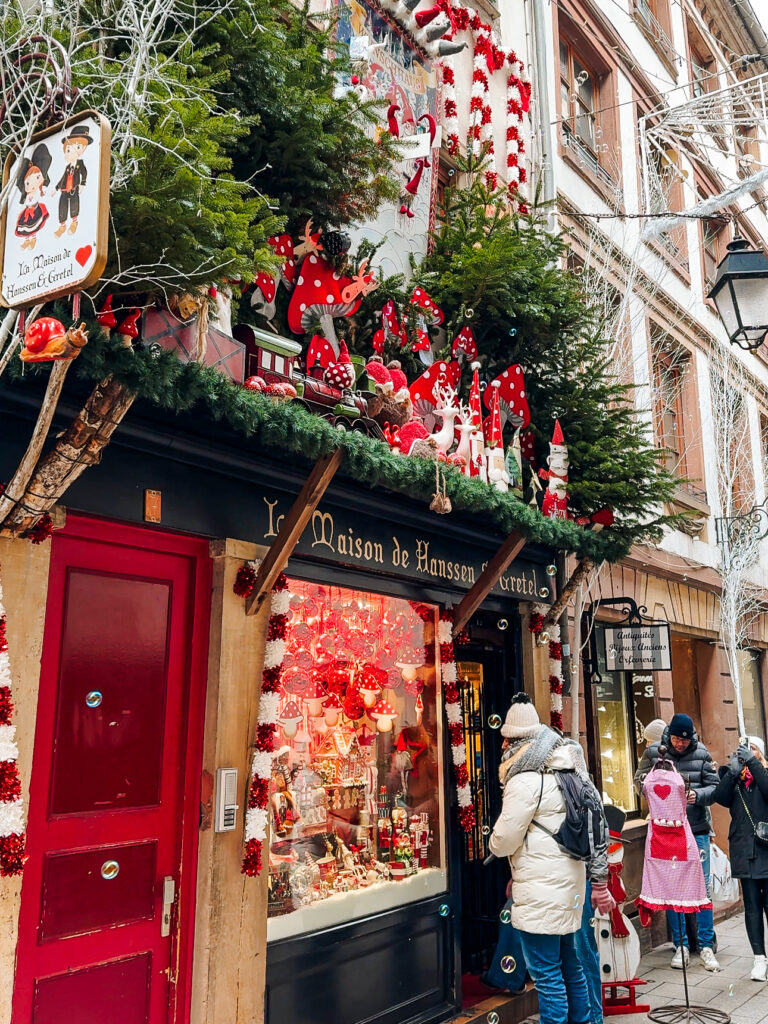 Whimsical Hanssen & Gretel shop in Strasbourg decorated with red mushrooms, Christmas ornaments, and fairy tale figures.
