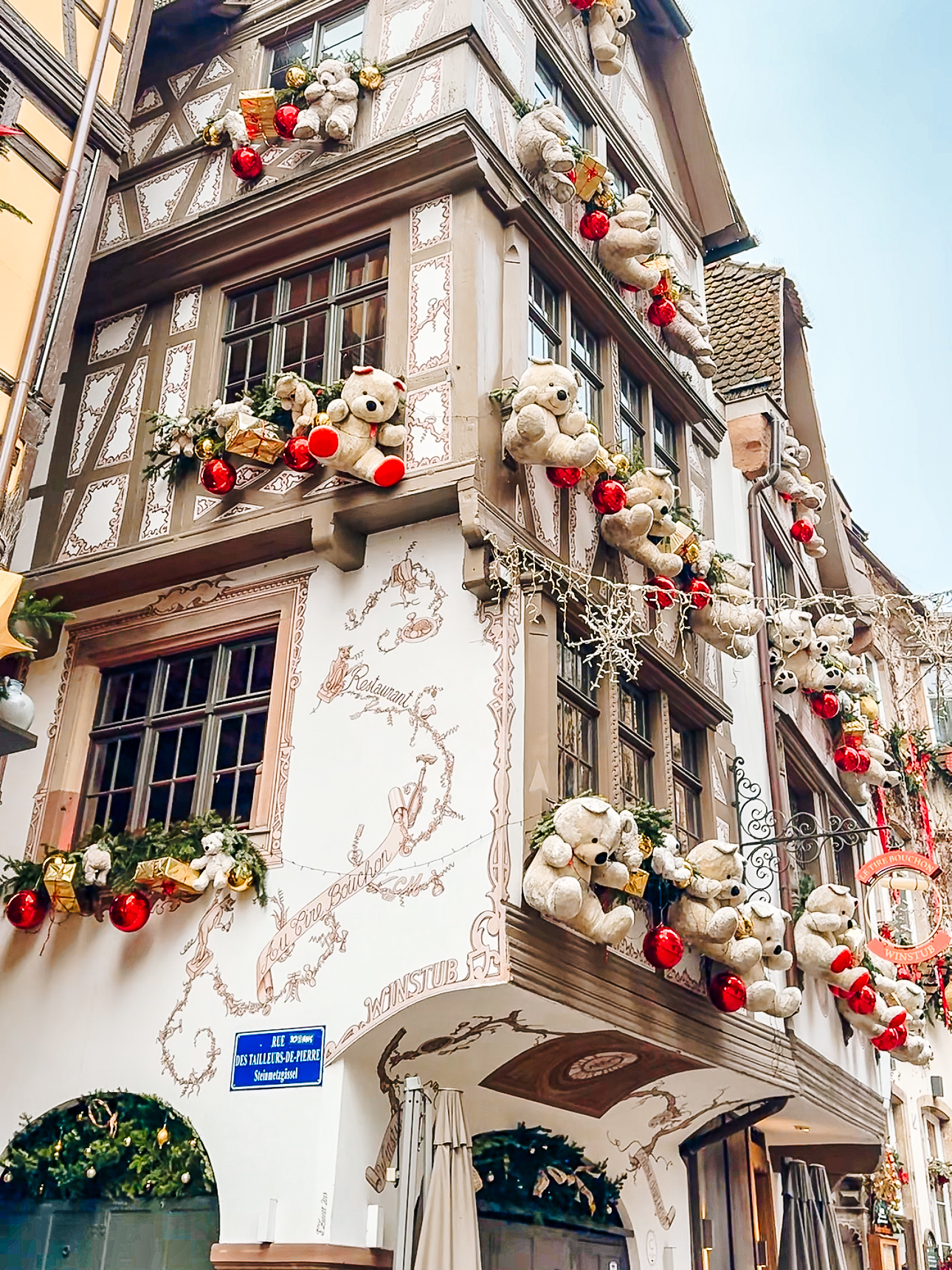 Famous Strasbourg half timbered house decorated with giant teddy bears, stars, and ornaments during Christmas.