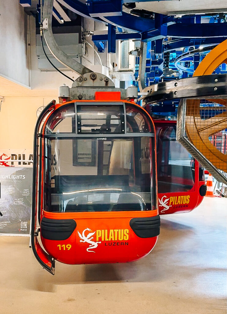 Close-up of a red Pilatus Luzern gondola cabin inside the station, ready for passengers.