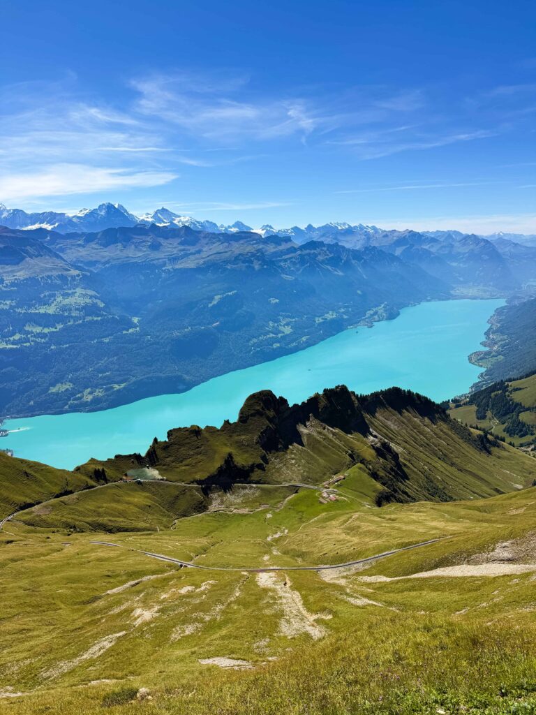 Aerial view of the turquoise waters of Lake Brienz surrounded by green alpine meadows and rugged mountain ridges from Rothorn Kulm.