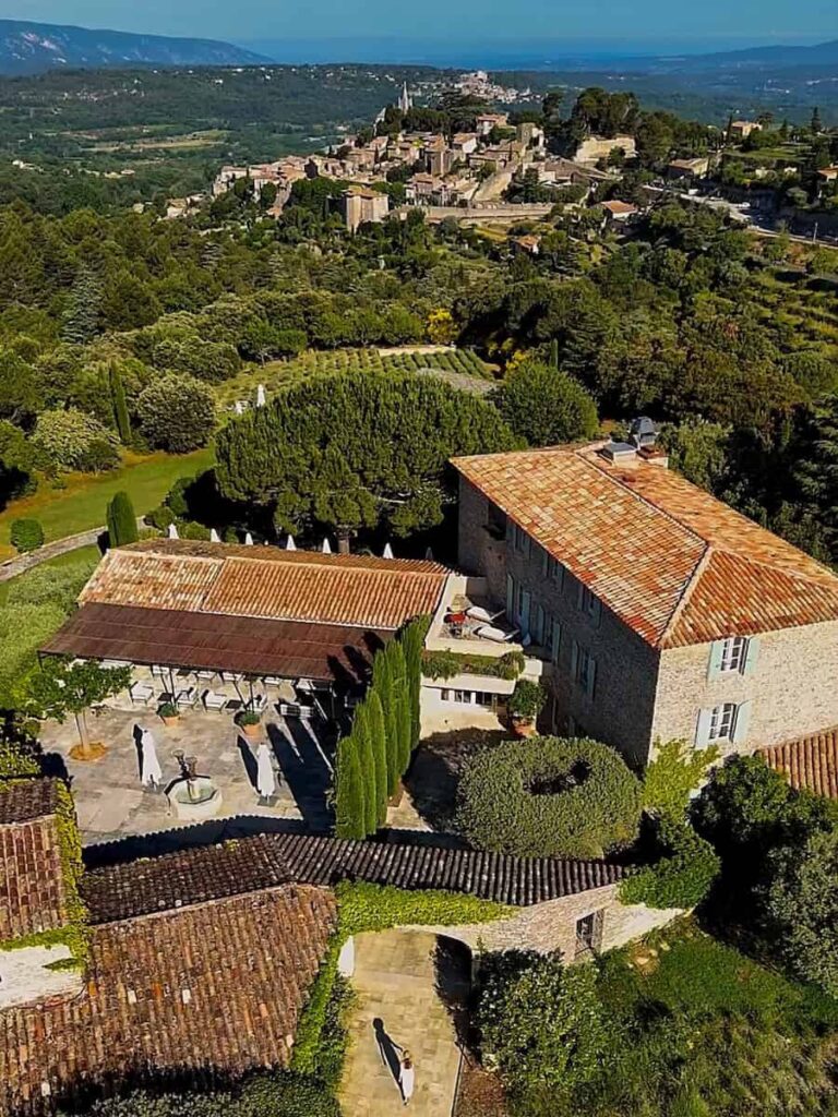 Aerial view overlooking Capelongue and the surrounding Luberon countryside with a hilltop village in the distance.