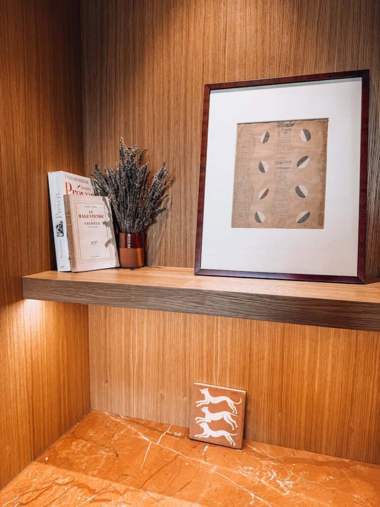 A wooden shelf styled with art, dried lavender, vintage books, and a framed print.