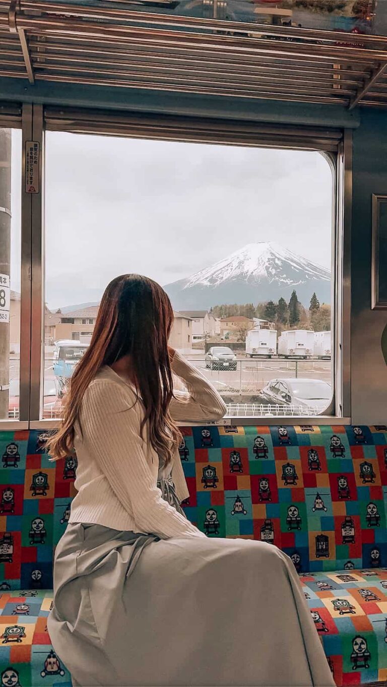 Japan train travel scene with a woman sitting by the window looking at Mount Fuji