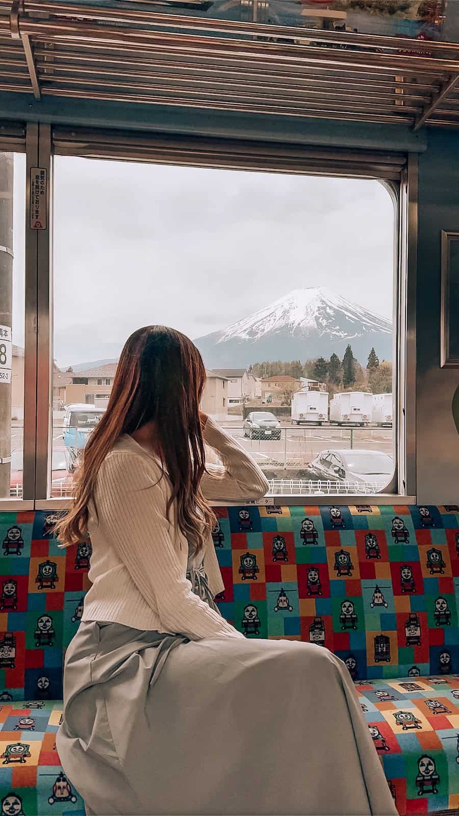 Japan train travel scene with a woman sitting by the window looking at Mount Fuji