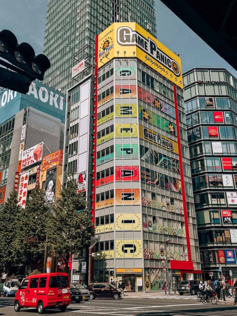 Game Panic arcade building in Shibuya Tokyo with colorful vertical signage and busy city intersection filled with cars and pedestrians