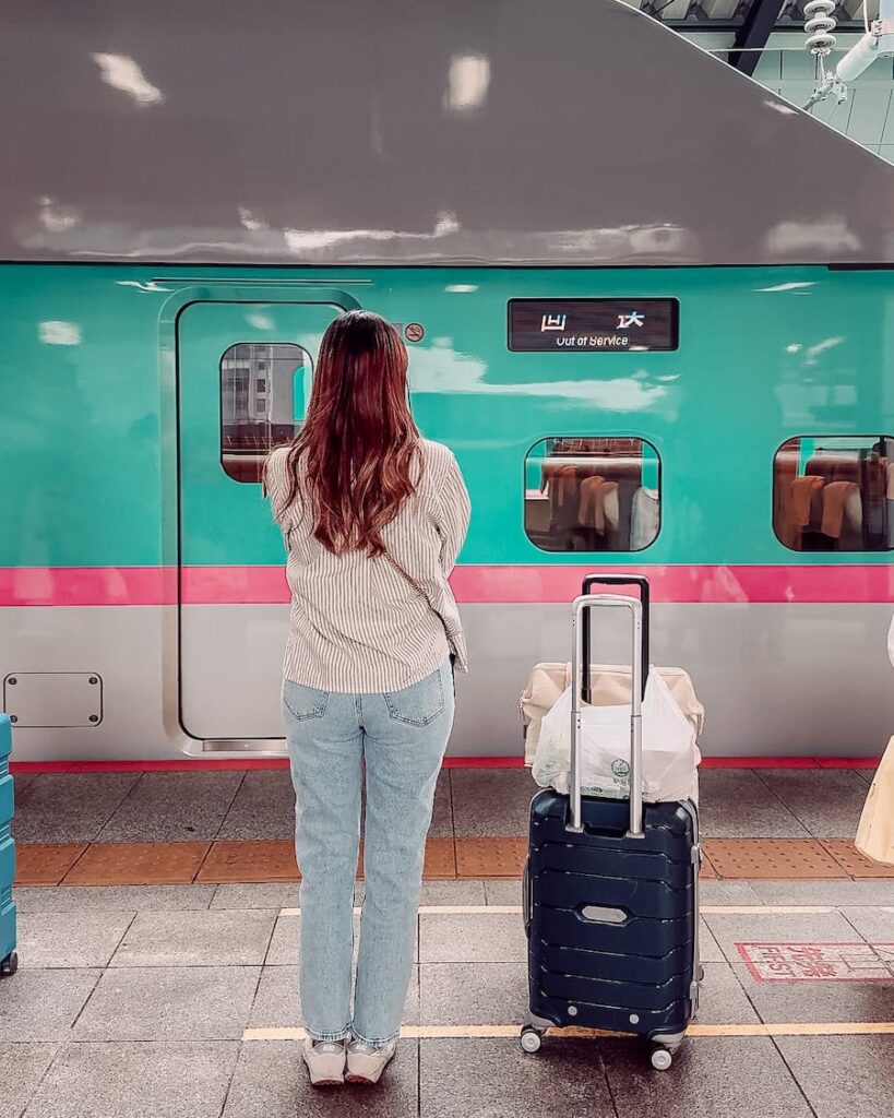 Woman standing on a Japanese train platform with luggage waiting for a Shinkansen bullet train in Japan, depending on the reliable Japan train travel system. 
