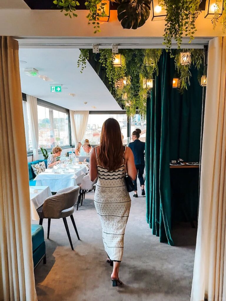 Guest walking into Le Roof restaurant at Five Seas Hotel Cannes beneath a lush green ceiling and warm lighting