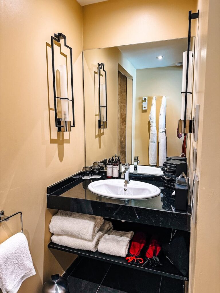 Bathroom sink area at Five Seas Hotel Cannes with black stone countertop modern fixtures and plush towels