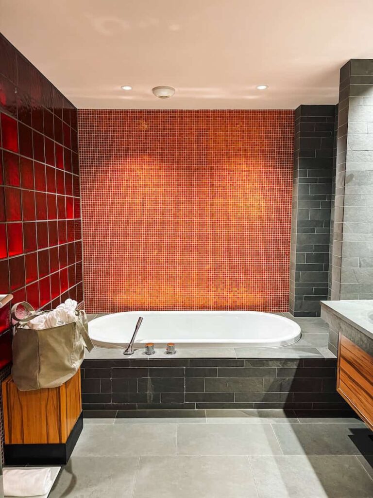 Modern bathtub at Hotel Krallerhof with red mosaic tiles dark stone flooring and minimalist design