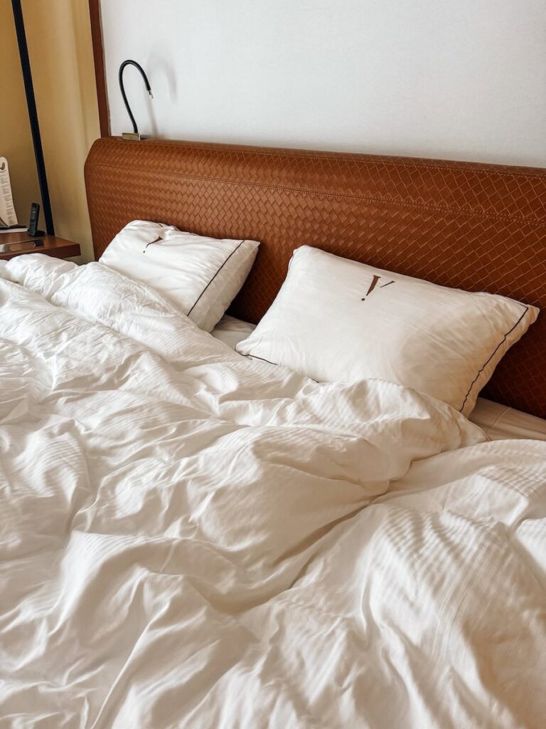 Luxury king bed with crisp white linens and leather headboard inside Five Seas Hotel Cannes room