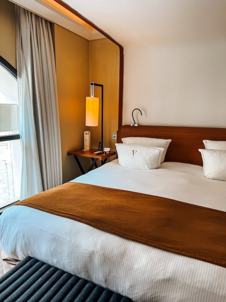 Luxury hotel bed at Five Seas Hotel Cannes with leather headboard warm tones and arched window