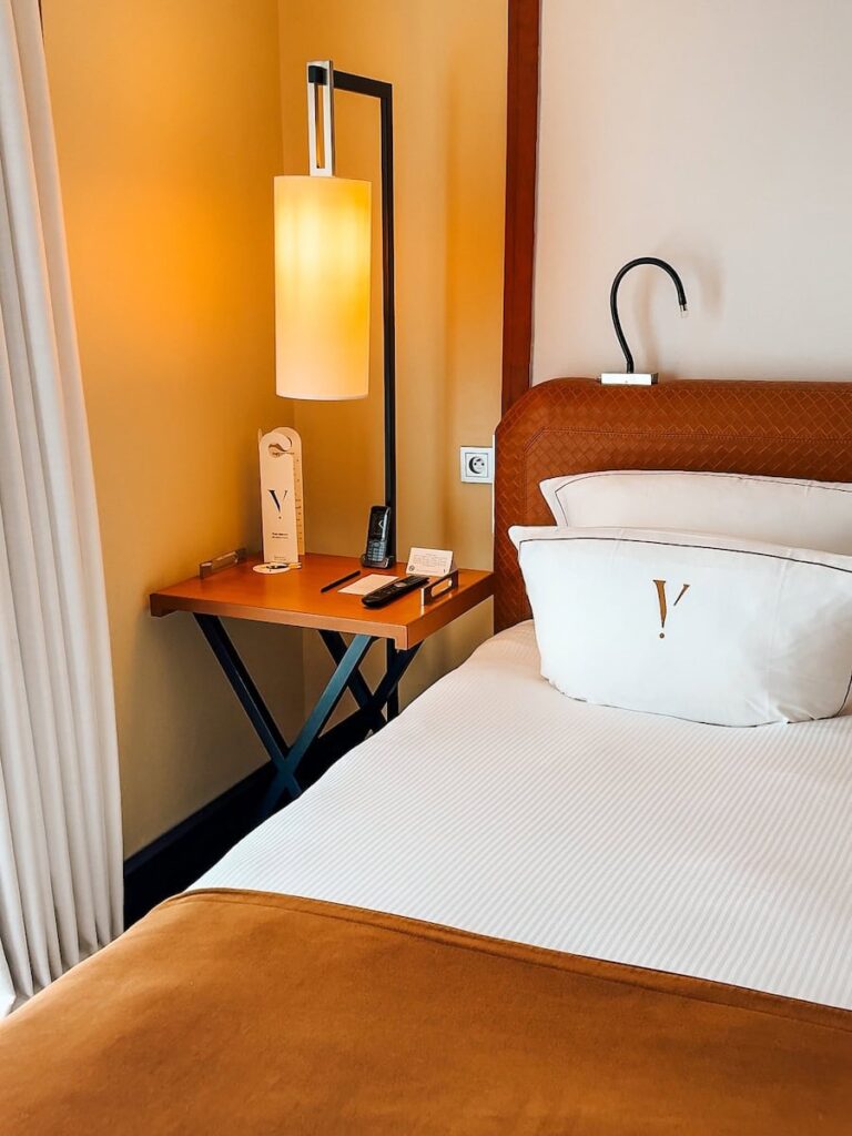 Bedside corner at Five Seas Hotel Cannes showing leather headboard warm lighting and nightstand details