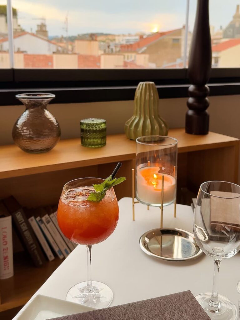 Cocktail and candlelit table at Le Roof restaurant with evening views over Cannes rooftops