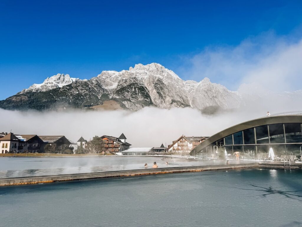 Infinity pool at Hotel Krallerhof with guests soaking while overlooking fog covered alpine village and mountains