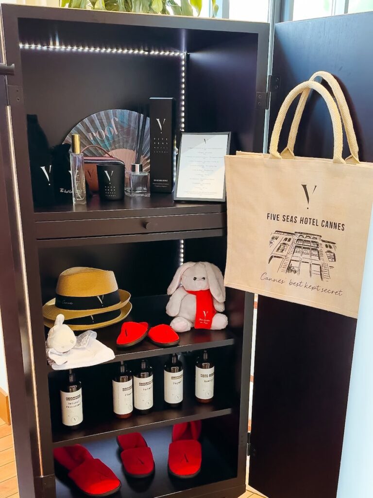Hotel merchandise display at Five Seas Hotel Cannes featuring signature scents slippers tote bags and branded accessories