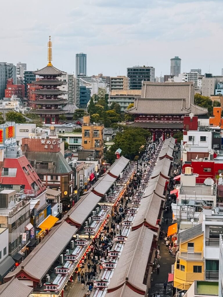 Aerial view of Nakamise Street in Asakusa Tokyo lined with traditional market stalls leading to Sensoji Temple with crowds of visitors walking below