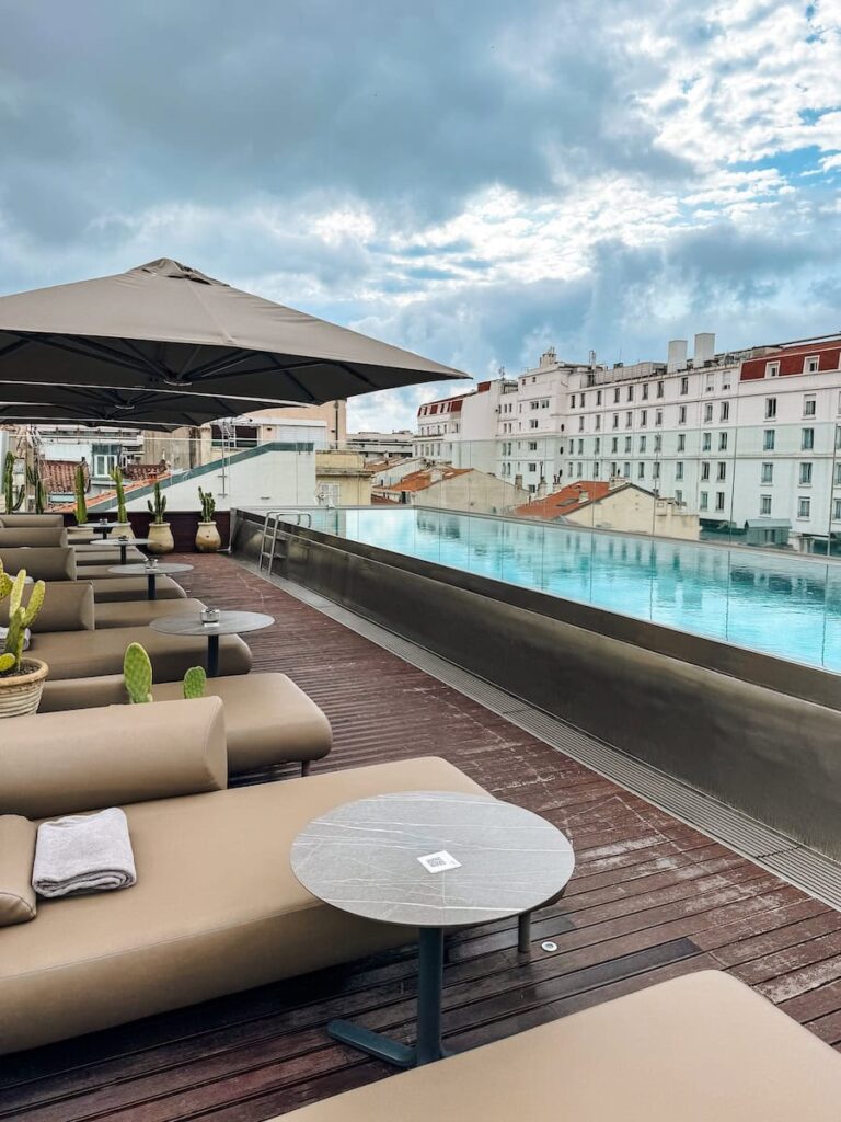 Rooftop terrace pool at Five Seas Hotel Cannes with sun loungers and panoramic views of Cannes under a cloudy sky