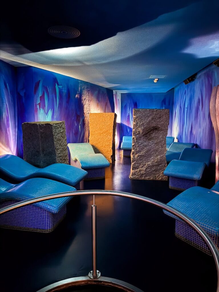 Atmospheric relaxation room at Hotel Krallerhof with blue loungers textured stone elements and ambient lighting