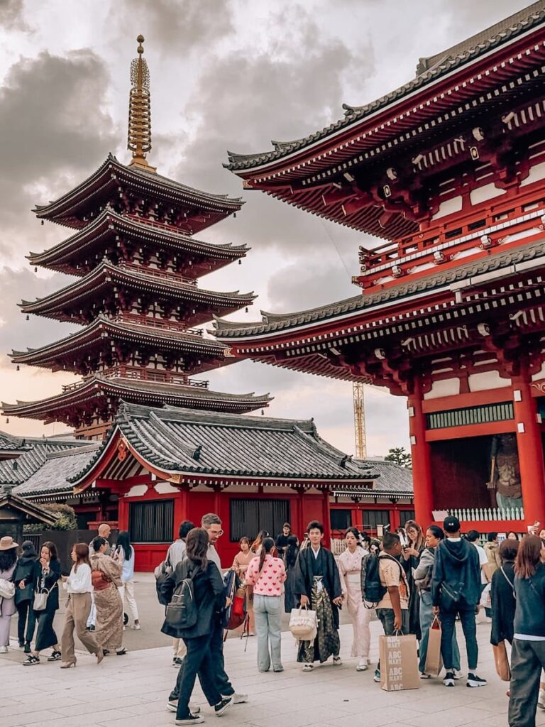 Five story pagoda and temple buildings at Sensoji Temple in Asakusa Tokyo with visitors walking through the historic temple grounds