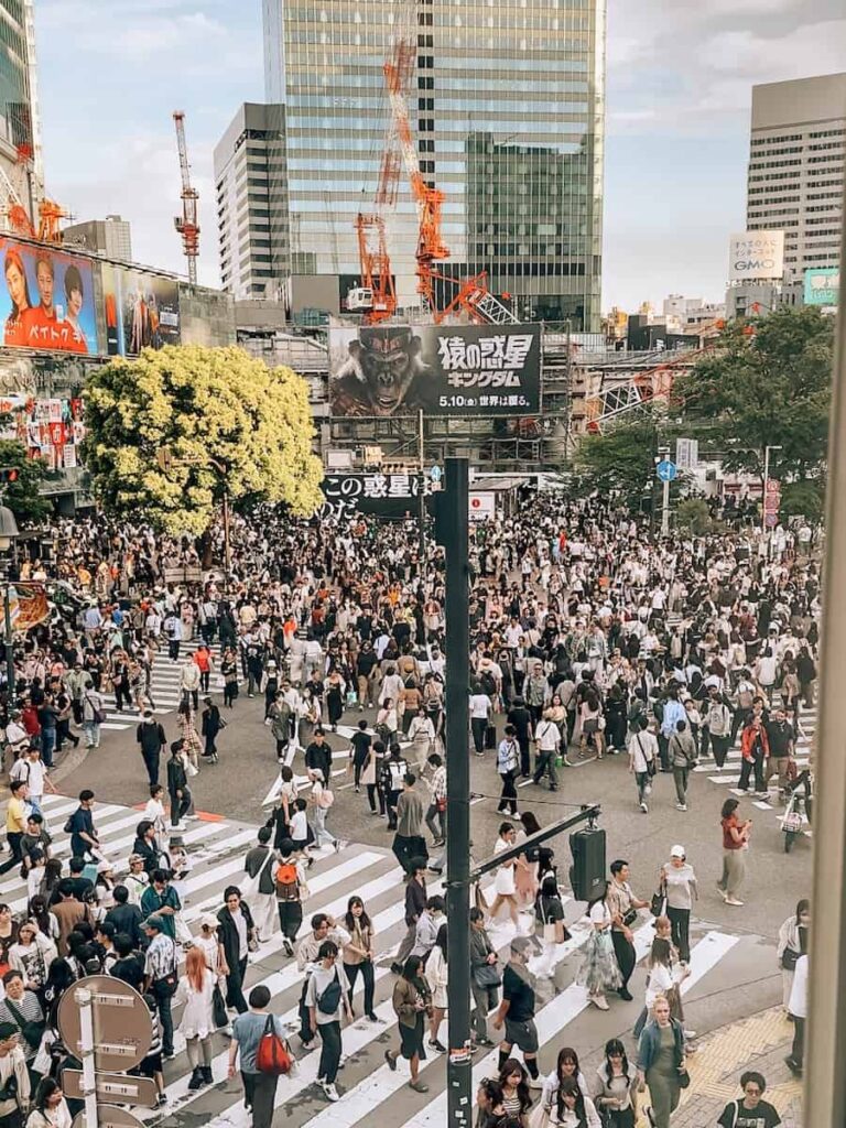Crowds of people crossing Shibuya Scramble Crossing in Tokyo with busy crosswalks and city buildings surrounding the famous intersection