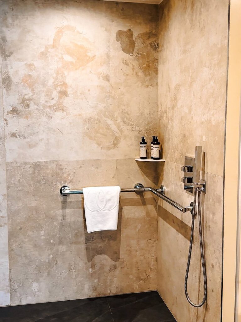 Walk in shower at Five Seas Hotel Cannes featuring stone walls chrome fixtures and spa style amenities
