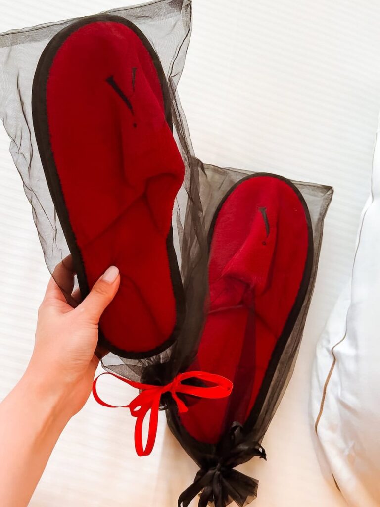 Plush red hotel slippers at Five Seas Hotel Cannes presented as a welcome amenity on the bed