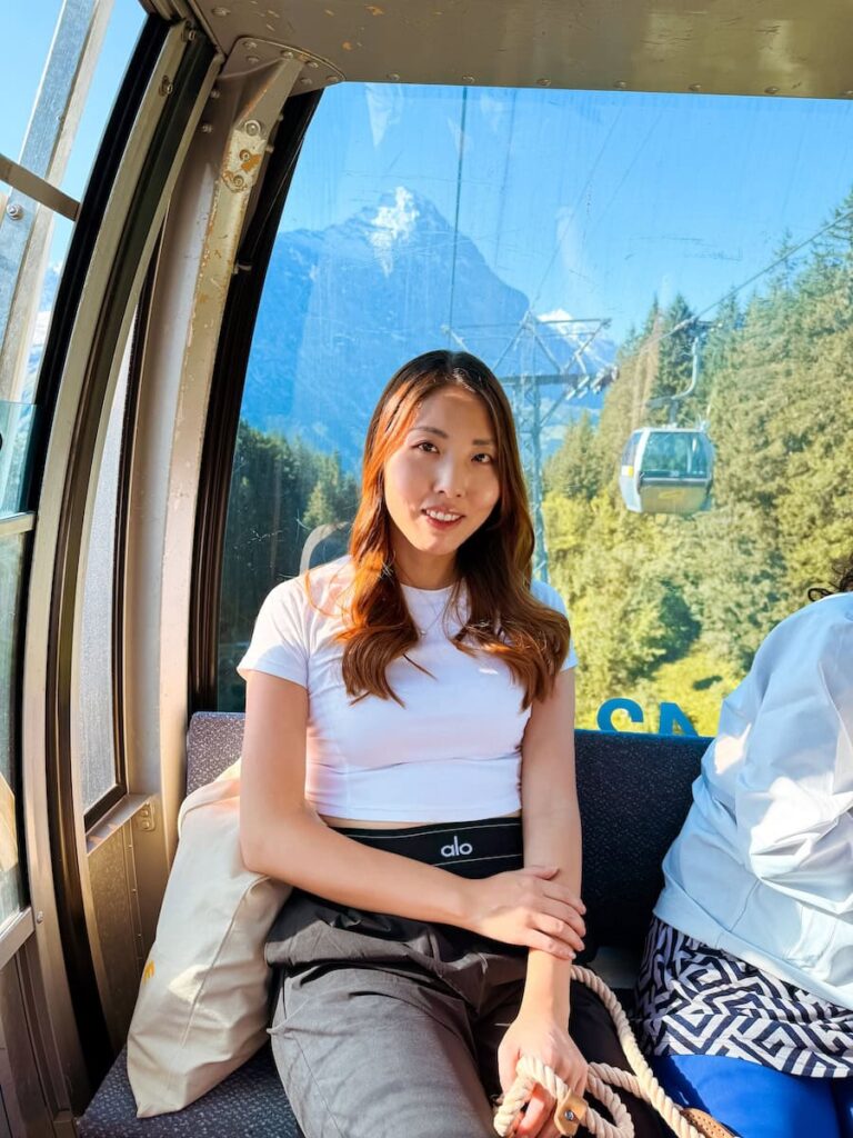 Woman riding the Grindelwald First gondola with views of the Eiger mountain in the Swiss Alps