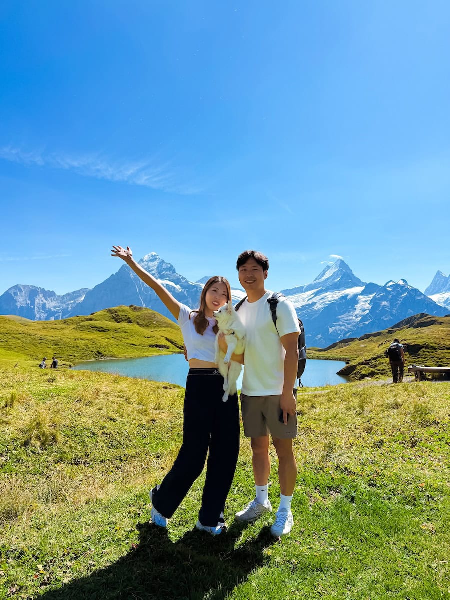 Couple holding their dog at Lake Bachalpsee with Eiger mountain backdrop in the Swiss Alps