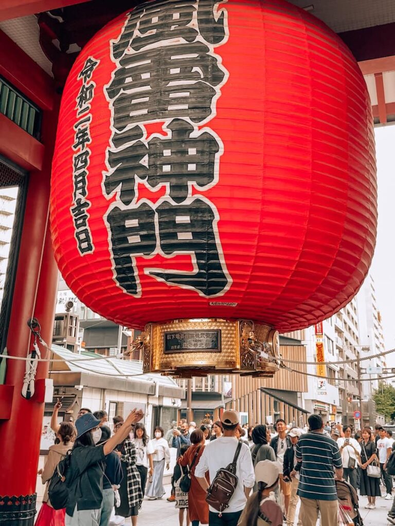 Large red Kaminarimon lantern at Senso ji Temple in Asakusa Tokyo with visitors gathered beneath the iconic entrance gate
