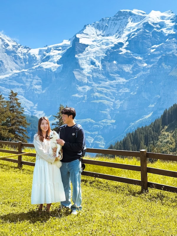 Author and husband and their dog standing in winteregg with swiss alps behind them