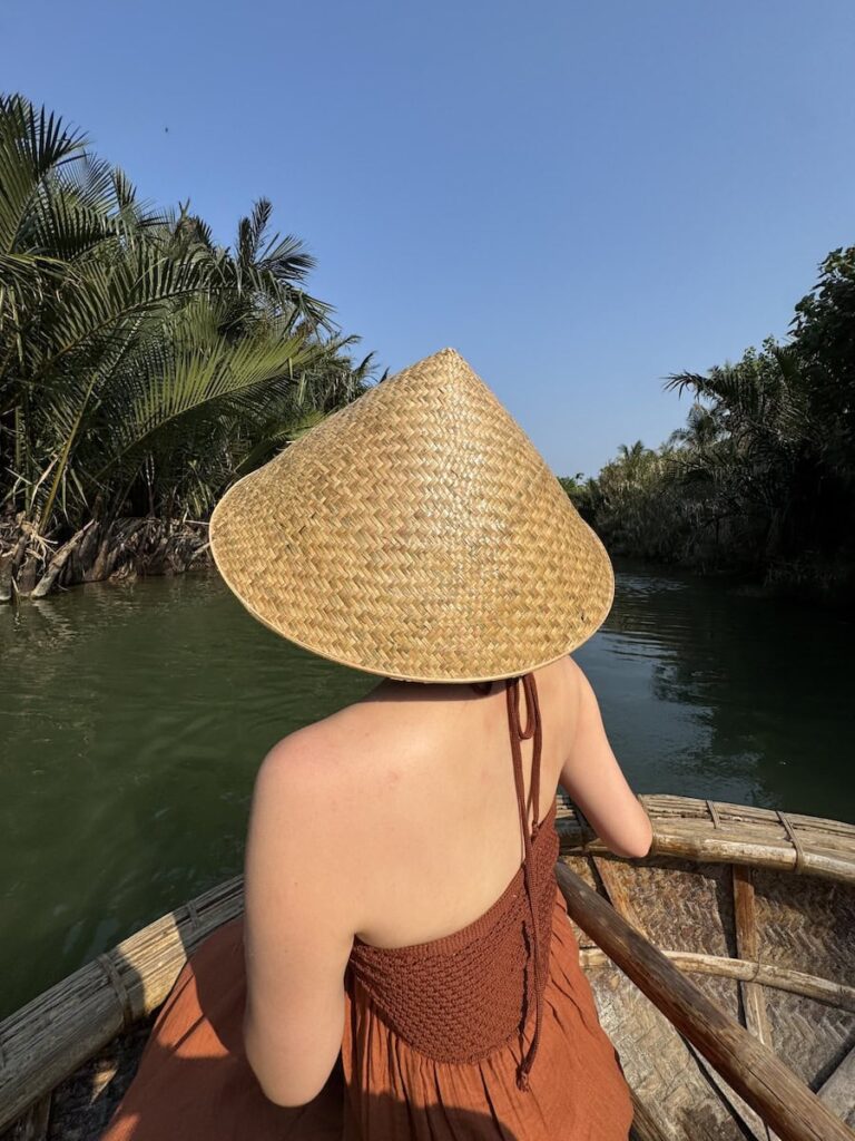 Woman wearing a Vietnamese conical hat riding in a basket boat through the coconut forest in Hoi An